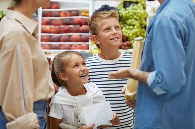 Crianças felizes, compras com os pais no supermercado