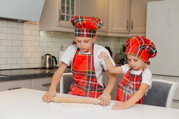 crianças felizes cozinham biscoitos de Natal em casa na cozinha com fantasia de chef irmão e irmã