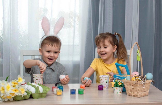Crianças felizes da Páscoa pintam e desenham ovos de Páscoa Crianças encantadoras se preparando para o feriado Menina e menino bonitos decoram ovos de Páscoa