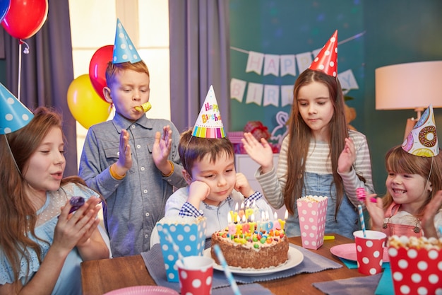 Crianças felizes em bonés de festa comemorando um aniversário