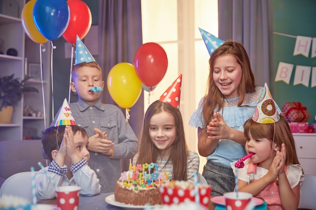 Crianças felizes em bonés de festa comemorando um aniversário