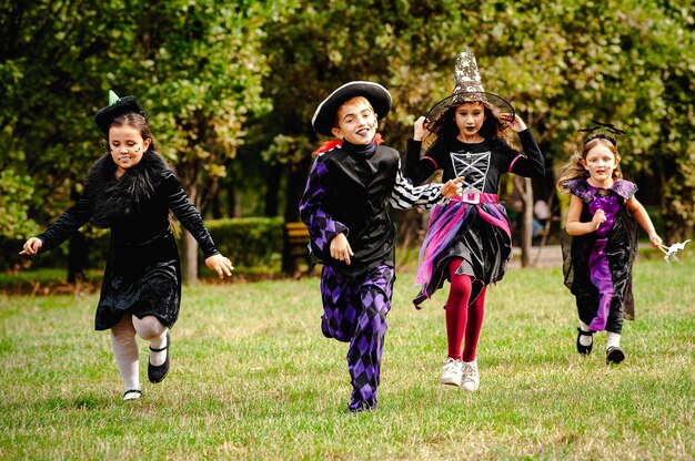 Crianças felizes em fantasias de halloween correndo no gramado