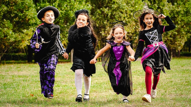 Crianças felizes em fantasias de halloween correndo no gramado