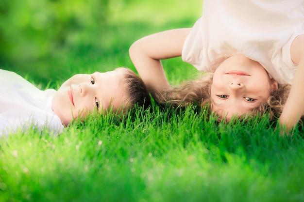 Crianças felizes em pé de cabeça para baixo na grama verde Crianças sorridentes se divertindo no parque primavera Conceito de estilo de vida saudável