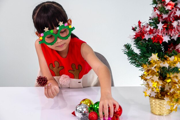 Crianças felizes em pijamas listrados vermelhos e verdes combinando decoram a árvore de Natal