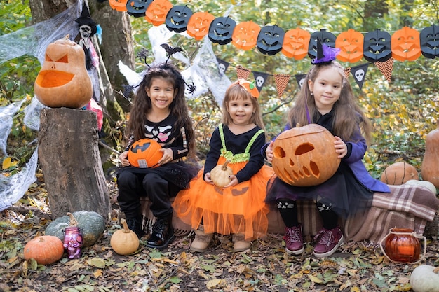 Crianças felizes em trajes de halloween se divertindo em decorações de halloween ao ar livre