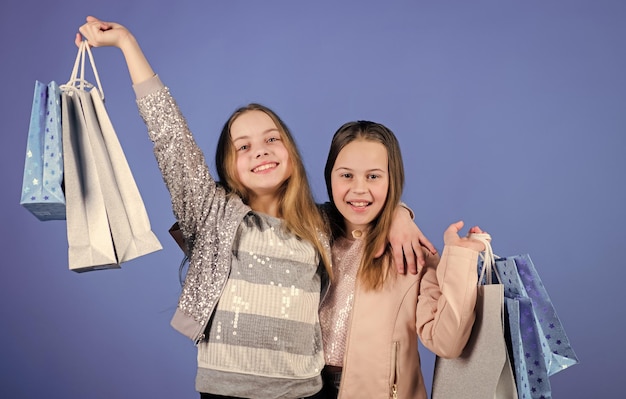 Crianças felizes Irmãzinhas desfrutando de compras on-line Meninas com sacolas de compras Vendas e descontos Irmandade e economia familiar em compras Moda infantil Compras em casa