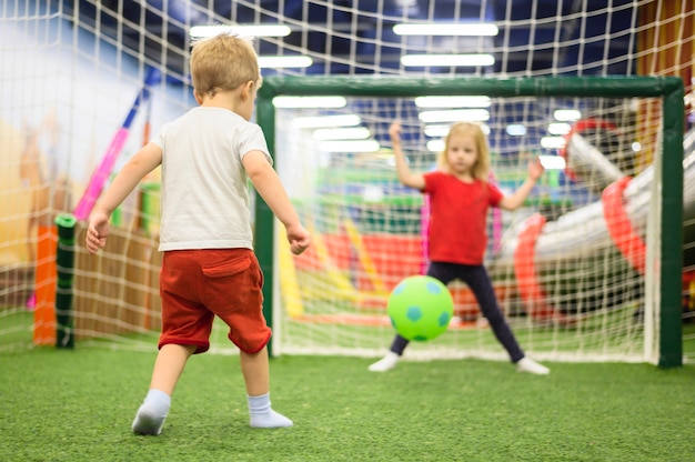 Foto crianças felizes jogando futebol dentro de casa