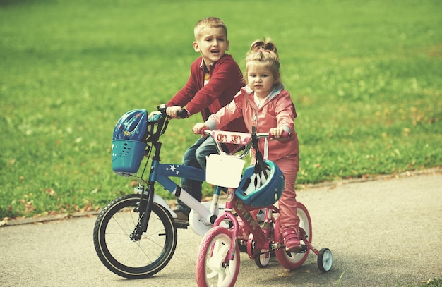 crianças felizes no parque, menino e menina na natureza com bicicleta se divertem