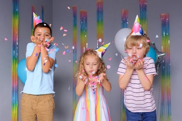 Foto crianças felizes se divertem nas férias e pulam em confetes coloridos
