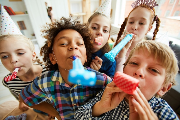 Crianças felizes, tocando chifres de festa