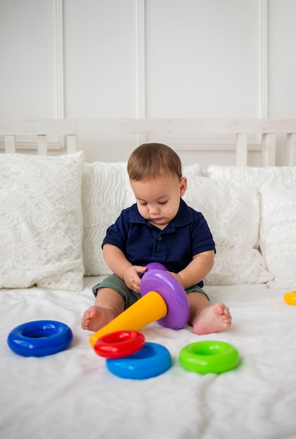 Crianças focadas em estudos de menino com brinquedo de pirâmide na cama branca