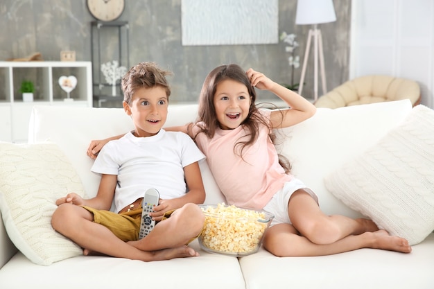 Crianças fofas assistindo TV no sofá em casa