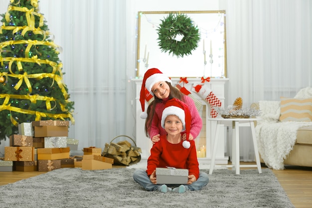 Crianças fofas com presente de Natal na sala de estar