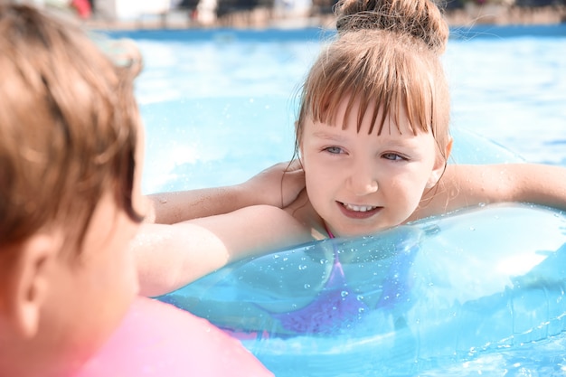 Crianças fofas nadando na piscina no dia de verão