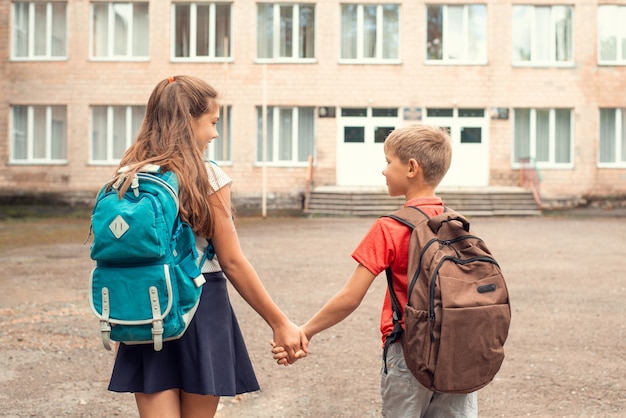 Crianças indo para a escola de mãos dadas