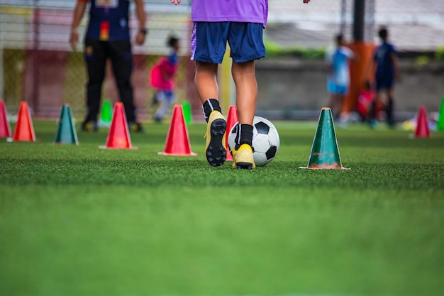 Crianças jogando cone de táticas de bola de futebol de controle no campo de grama com fundo de treinamento Treinamento de crianças no futebol