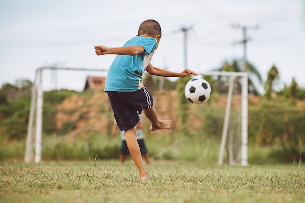 Crianças jogando futebol futebol para se exercitar no campo de grama verde