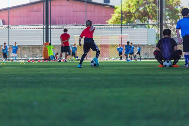 Crianças jogando táticas de bola de futebol de controle no campo de grama para treinamento