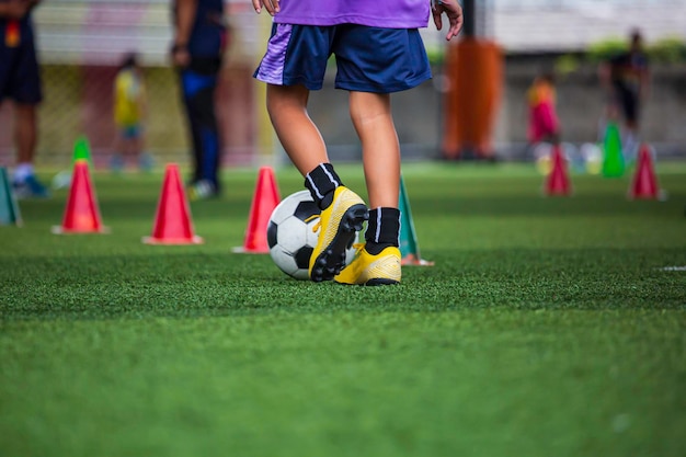 Crianças jogando táticas de bola de futebol de controle no campo de grama para treinamento