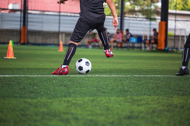 Crianças jogando táticas de bola de futebol de controle no campo de grama para treinamento