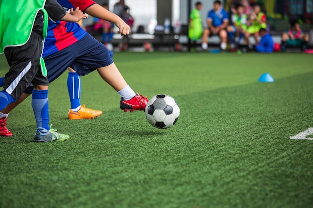 Crianças jogando táticas de bola de futebol no campo de grama com fundo de treinamento. Treinando crianças no futebol