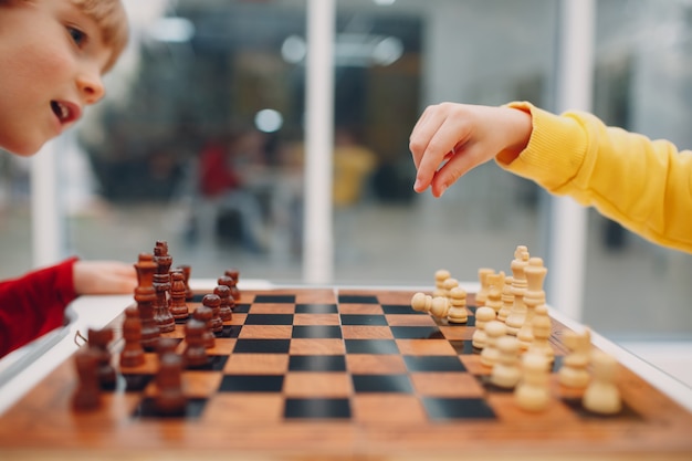 Crianças jogando xadrez no jardim de infância ou na escola primária. jogo  de xadrez infantil.