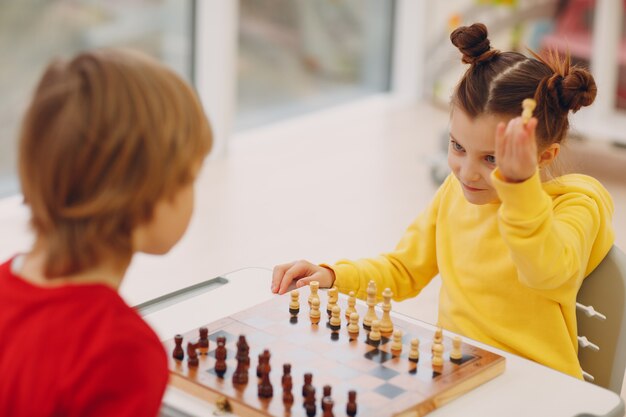 Crianças jogando xadrez no jardim de infância ou na escola primária