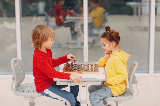 Crianças jogando xadrez no jardim de infância ou na escola primária