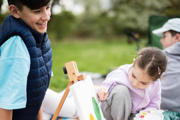 Crianças jovens e felizes da família se divertindo e curtindo ao ar livre na pintura de cobertores de piquenique no relaxamento do jardim primavera