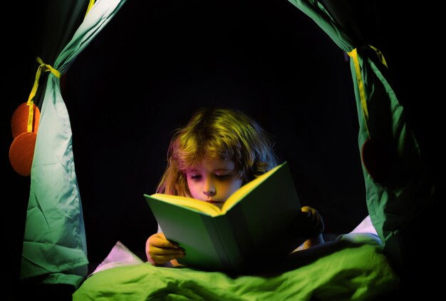 Foto crianças lendo livros sonhando criança na tenda das crianças lendo histórias para dormir conto de fadas ou conto de fades