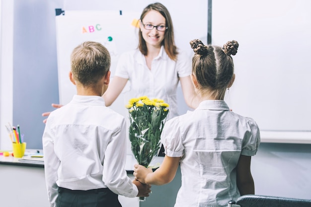 Crianças lindas, crianças em idade escolar com flores para os professores da escola em um feriado