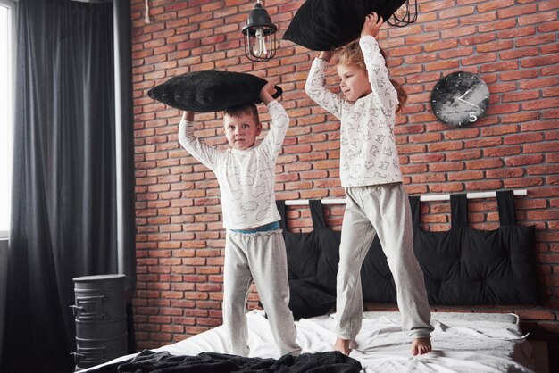 Crianças malcriadas Menino e menina fizeram uma briga de almofadas na cama do quarto. Eles gostam desse tipo de jogo