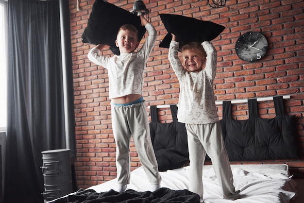 Crianças malcriadas Menino e menina fizeram uma briga de almofadas na cama do quarto. Eles gostam desse tipo de jogo