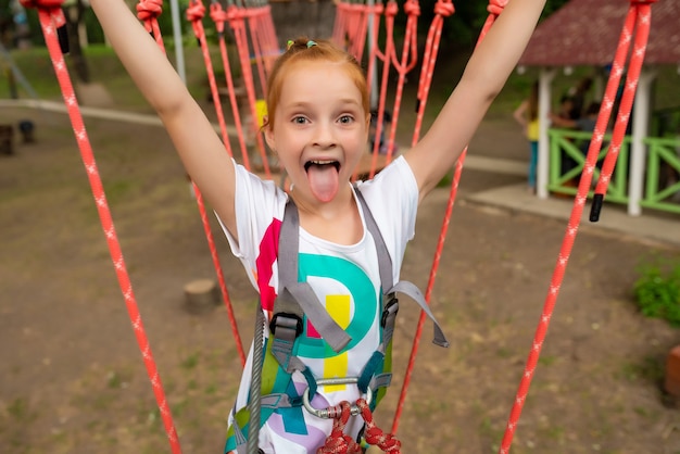 Foto crianças - menina corre uma pista de obstáculos em um parque de corda