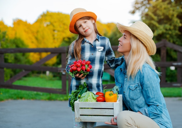 Crianças menina segurando a mãe uma cesta de legumes orgânicos frescos com o jardim em casa.