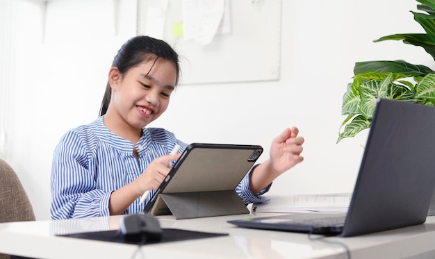 Crianças meninas asiáticas usando o tablet do computador portátil, estudando através do sistema de e-learning on-line. novo coronavírus normal.covid-19. distanciamento social. ficar em casa