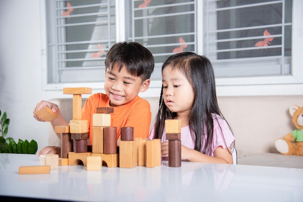 Crianças menino e menina brincando com a construção de blocos de madeira do construtor