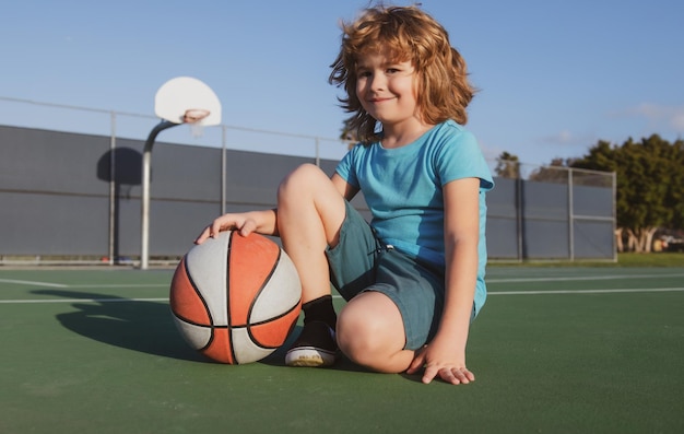 Crianças menino jogando basquete Atividade esportiva infantil Menino sorridente joga bola