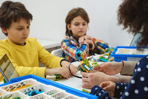 Crianças multiétnicas no robô de codificação de aula de tecnologia no tablet