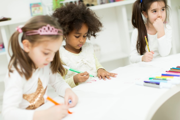 Crianças multirraciais de desenho na sala de jogos