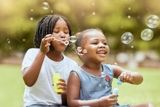 Foto Namoradinhas negras sentadas em banco de madeira e brincando ao ar  livre. Conceito de infância. Ideia de amizade. Estilo de vida infantil  moderno. Meninas morenas cacheadas alegres. Ensolarado durante o dia –