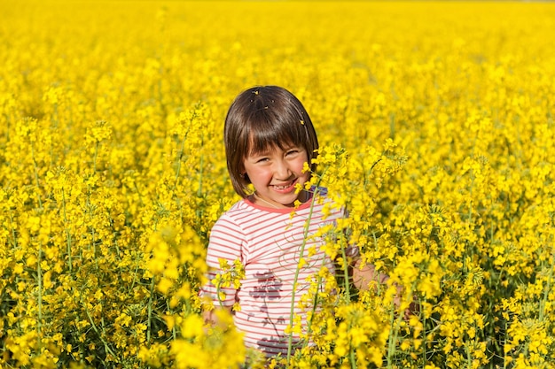 Crianças no campo com as flores amarelas da estupro