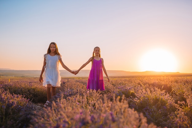 Crianças no campo de flores de lavanda ao pôr do sol nos vestidos