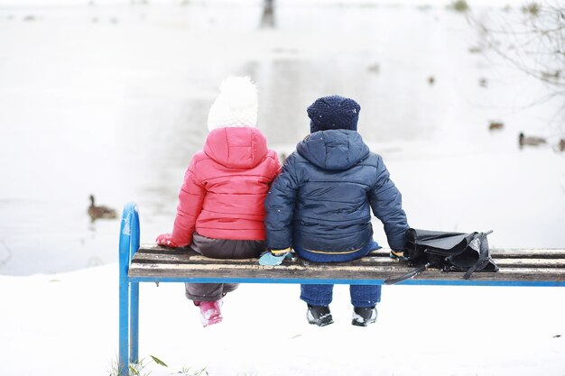 Crianças no parque de inverno brincam com a neve