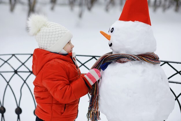 Crianças no parque no inverno. As crianças brincam com neve no parque infantil. Eles esculpem bonecos de neve e deslizam pelas colinas.