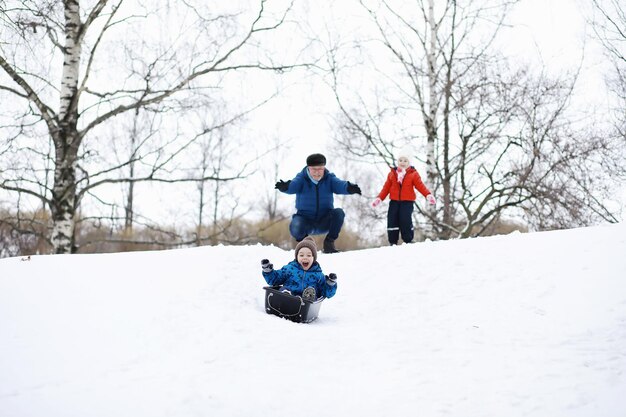 Crianças no parque no inverno. As crianças brincam com neve no parque infantil. Eles esculpem bonecos de neve e deslizam pelas colinas.