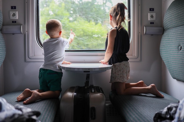 Crianças no trem olham pela janela Viajando com crianças