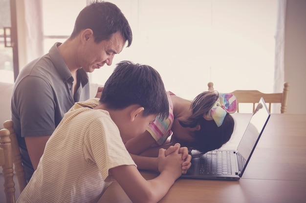 Crianças orando com pais e mães com laptop, família e crianças adoram online juntos em casa