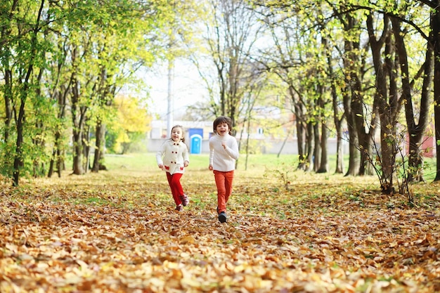 Crianças para uma caminhada no parque de outono Folha cai no parque Family Fall Happiness